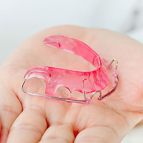 orthodontist holding a retainer in Mississauga